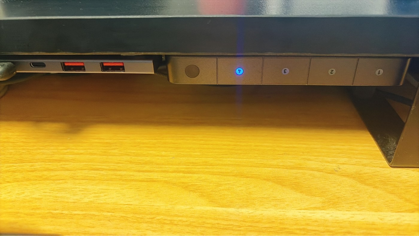 デスクシェルフの裏にマグネットで浮かせて取り付けた切替器（右側）